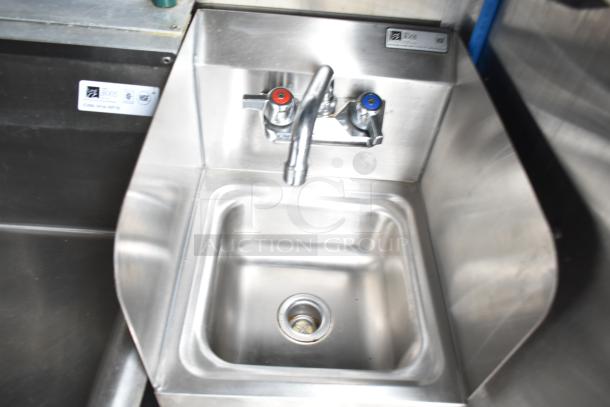 Stainless steel sink with dual-handled faucet in a commercial kitchen trailer, featuring a Boos label.