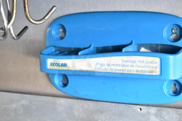 Blue Ecolab sanitizer test station mounted in a mobile kitchen trailer, indicating hygiene compliance equipment.