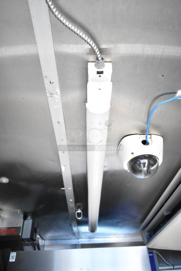 Interior view of commercial mobile kitchen trailer ceiling featuring a fluorescent light fixture and security camera.