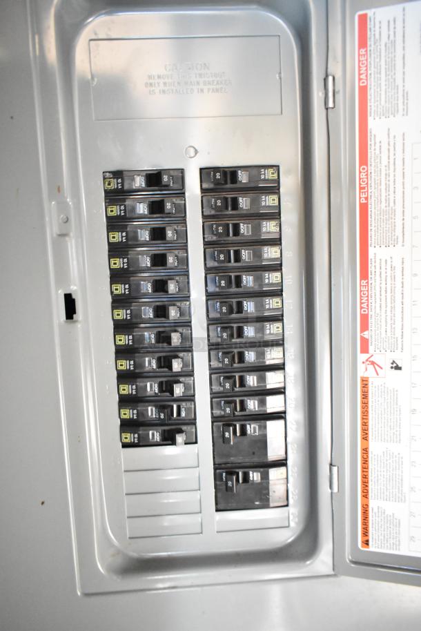 Electrical panel inside commercial mobile kitchen trailer, showing multiple circuit breakers and safety warnings.