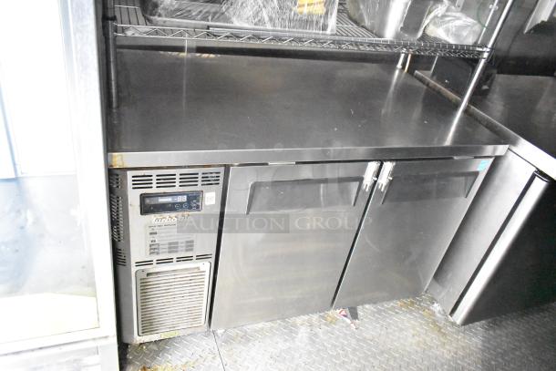 Commercial mobile kitchen trailer interior with refrigeration unit, featuring a CaptiveAire hood and Pitco propane fryers.