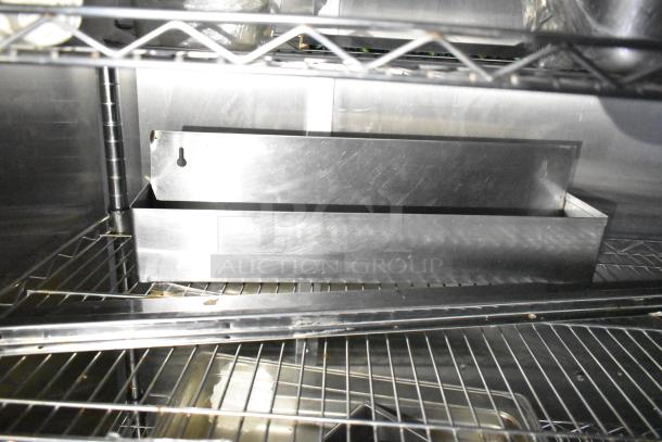 Commercial mobile kitchen trailer interior, featuring a stainless steel CaptiveAire hood system and shelving.