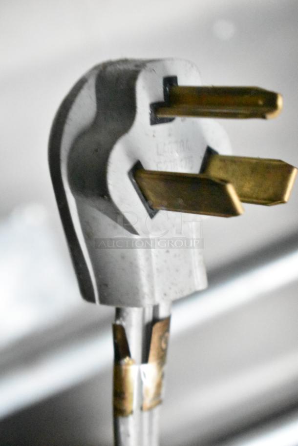 Close-up of an electrical plug with visible prongs and markings, part of a commercial kitchen trailer setup.