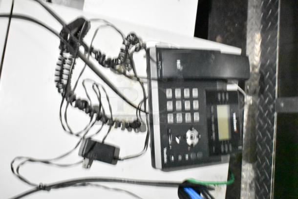 Blurred image showing a desk phone and tangled cords, possibly unrelated to the mobile kitchen trailer described.
