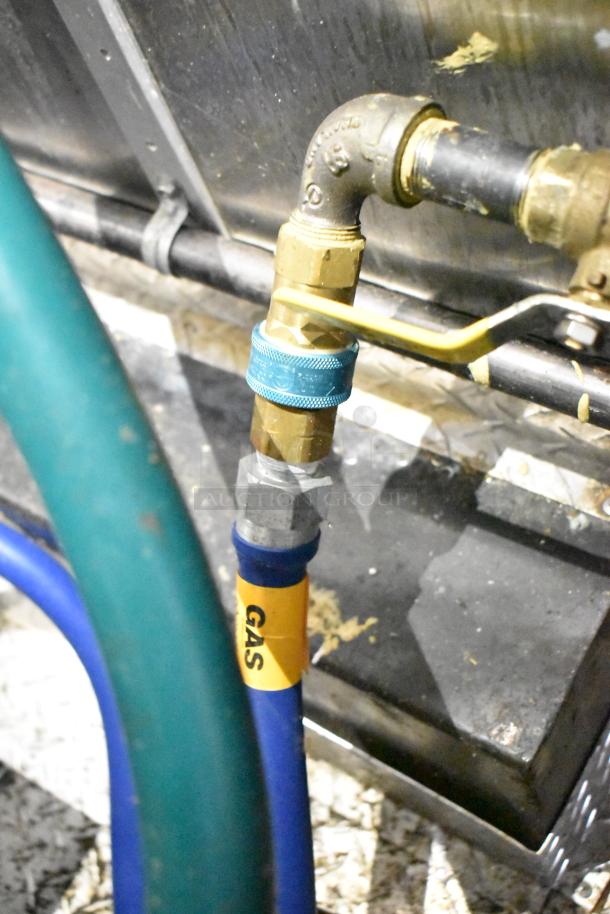 Gas connection inside a commercial mobile kitchen trailer showing a blue gas hose labeled "GAS" with brass fittings.