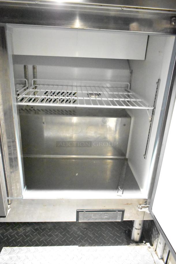 Commercial mobile kitchen trailer interior showing a stainless steel and white refrigerator space with wire shelf.