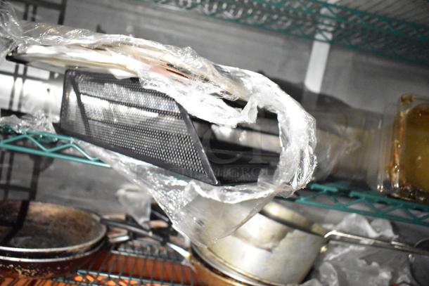 Commercial mobile kitchen trailer with CaptiveAire hood, Pitco fryers, and refrigeration. Shelving with kitchen equipment visible.