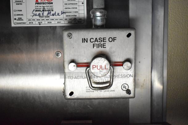 Fire suppression system control in a commercial mobile kitchen trailer, marked "In Case of Fire" with a pull handle.