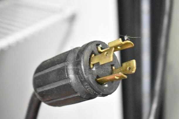 Close-up of power plug for the 2020 True GDM-49F-HC commercial cooler, showing prongs and black casing.