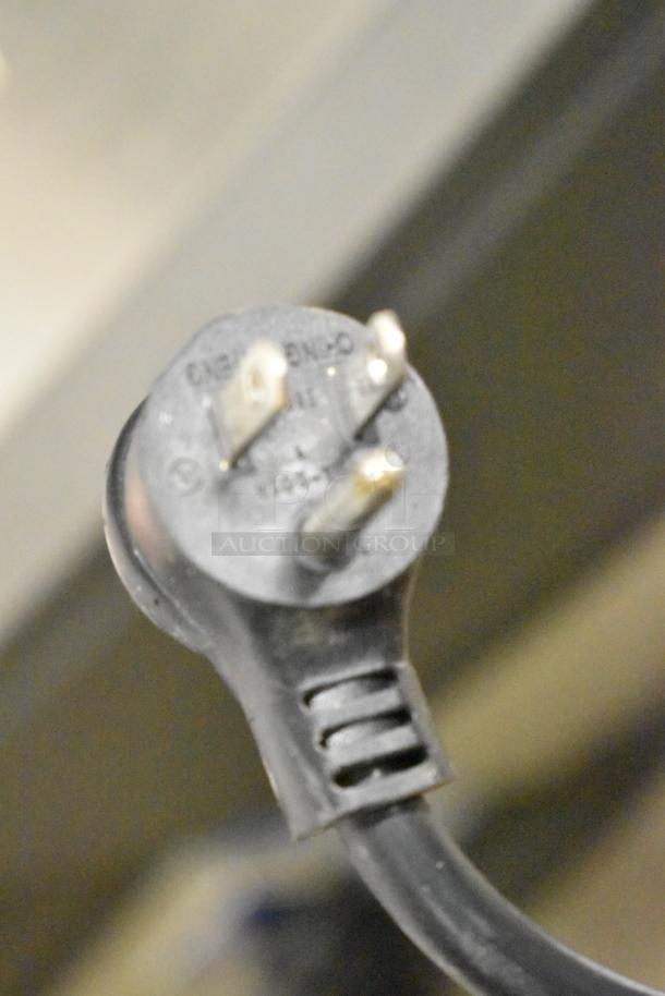 Close-up of a three-prong plug from a True GDM-49-HC cooler, showing electrical specifications and plug details.