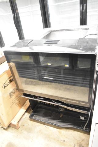 Commercial countertop beverage dispenser, black, glass front, 115 volts, 1 phase, used condition, KoolMore label visible.