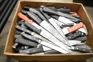 Box of 80 sharpened stainless steel knives, including chef knives, with black and red handles. Worn condition.
