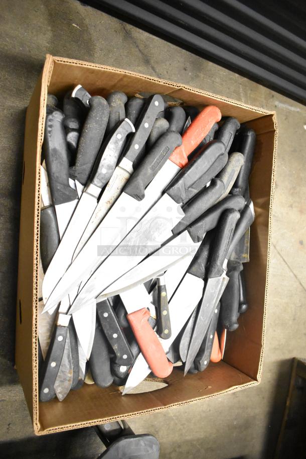Cardboard box containing 80 sharpened stainless steel knives, including chef knives, with diverse black and red handles.