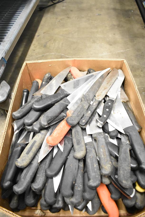 Box of 80 sharpened stainless steel knives, including chef knives, with black and orange handles. Used condition.