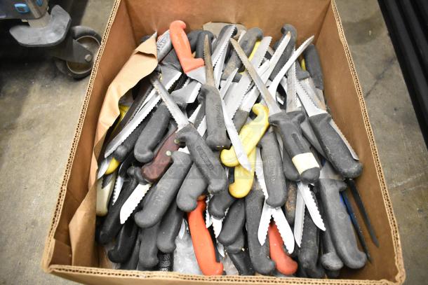 Box of 80 sharpened stainless steel knives, including serrated, with mixed handle colors, showing visible wear.