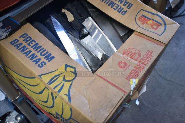 Box of 100 sharpened stainless steel knives, including a chef knife, in a repurposed banana box. Handle with care label visible.