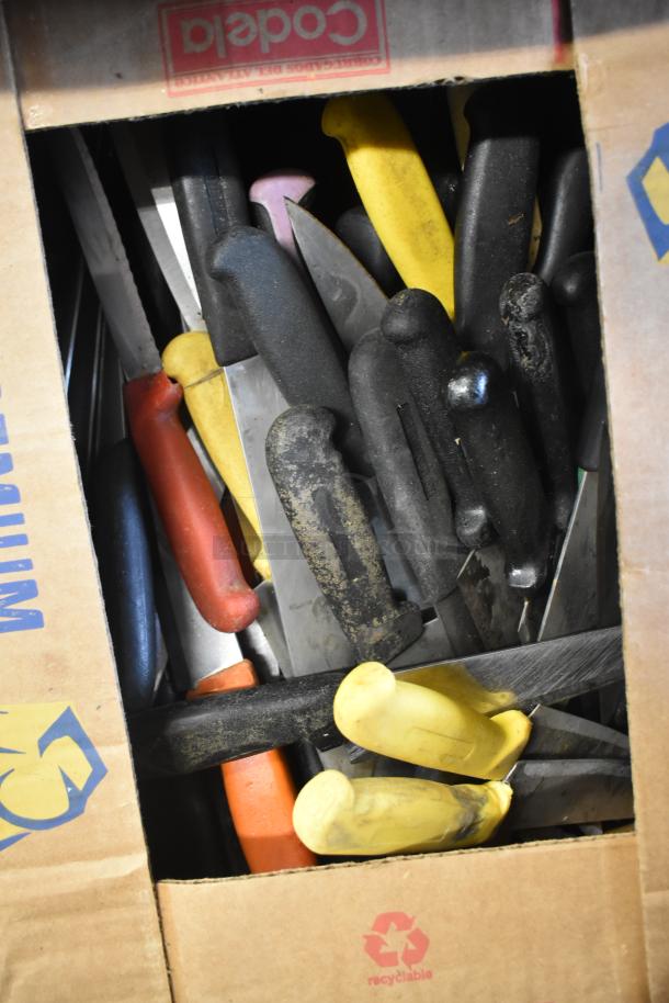 Box of 100 sharpened stainless steel knives with assorted colored handles, including chef knife.