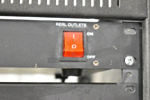 Close-up of AV cabinet featuring a red power switch labeled "REAL OUTLETS," part of a Pyle PCI-800 power conditioner.