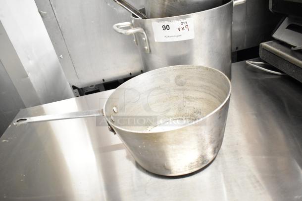 Nine metal cookware items, including sauce pots and a stock pot. Visible wear. Label reads "90 QTY Vx9."