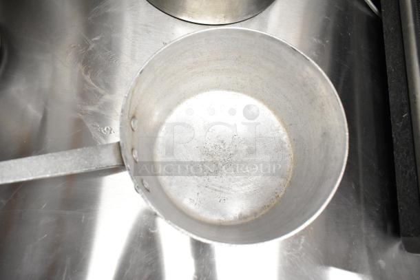 Set of nine cookware items, including sauce pots and a stock pot, in used condition with visible wear.