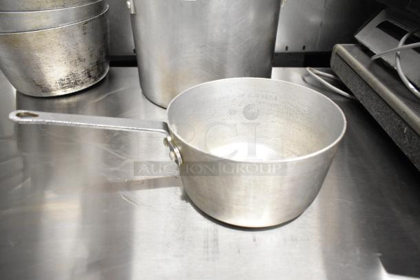 Set of 9 aluminum pots, including sauce and stock pots. Used condition with wear marks. Ideal for bulk cooking.