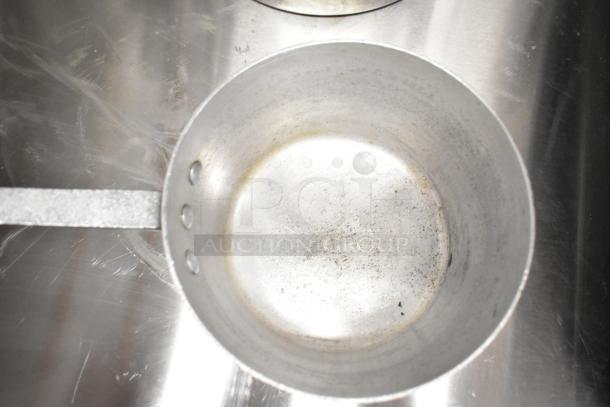 Aluminum sauce pot with handle, used condition, minor surface marks, visible circular base pattern.