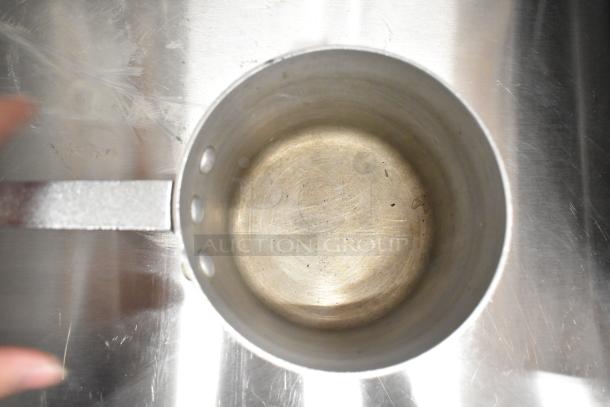 Overhead view of a metal sauce pot, showing worn interior. Part of a lot of 9 cookware items for auction.