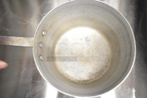 Worn aluminum sauce pot with riveted handle, part of a lot of 9 items including stock pot. Visible patina and scratches.