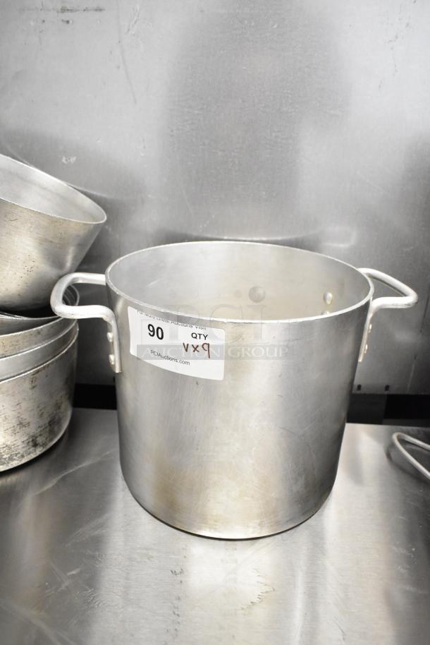 9 metal pots, including a sauce pot and stock pot, showing wear; label indicates auction lot quantity of 9.