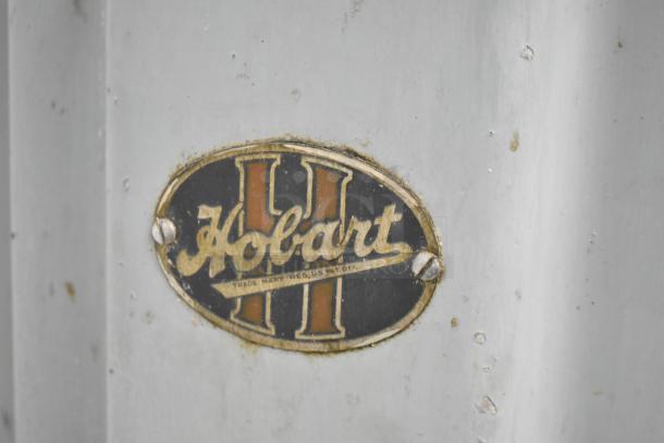 Hobart Commercial Floor Meat Saw with visible logo plate, showing signs of wear. Ideal for high-volume butchery.