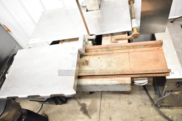 Hobart commercial floor-style meat saw with a metal table, showing signs of rust and wear. Item tag visible.