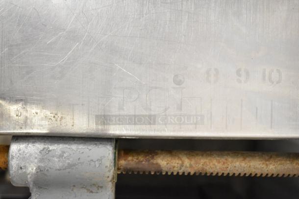 Hobart commercial floor-style meat saw, stainless steel surface with measurement markings, showing light wear and rust on blade edge.