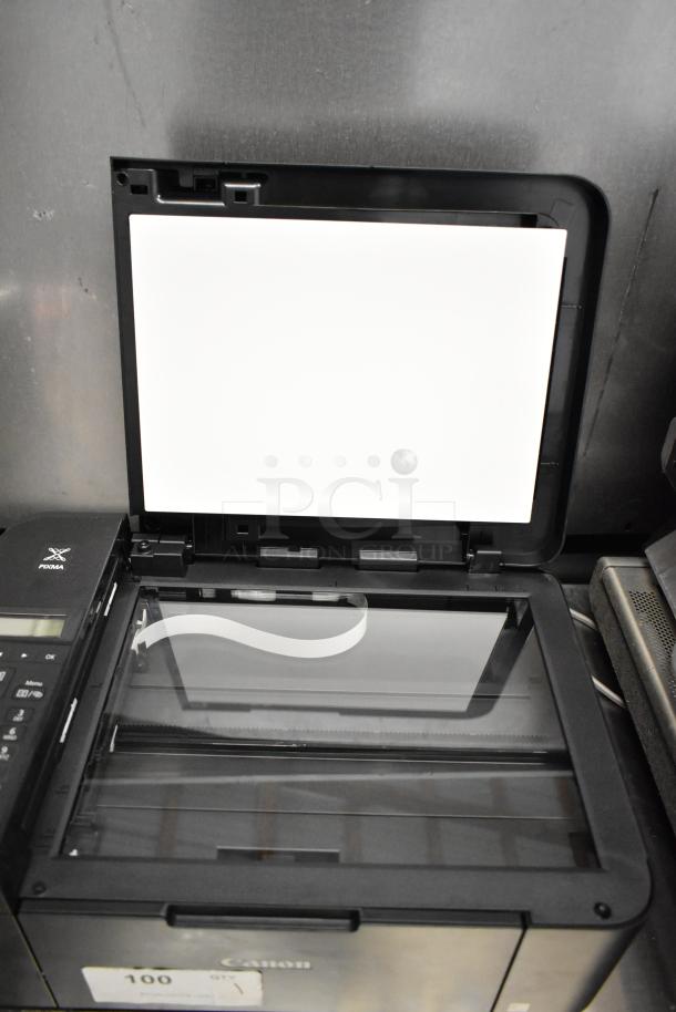 Canon K10546 multifunction printer, black, open scanner lid showing glass surface, in good condition with visible control panel.