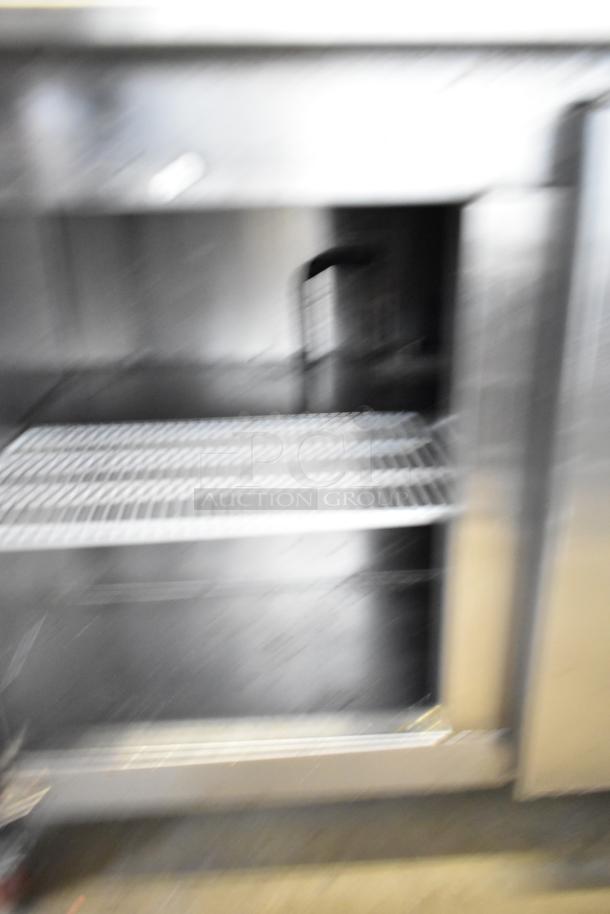 Blurry image of a Cooltech CTR-72BMB commercial sandwich salad prep table with open storage area.