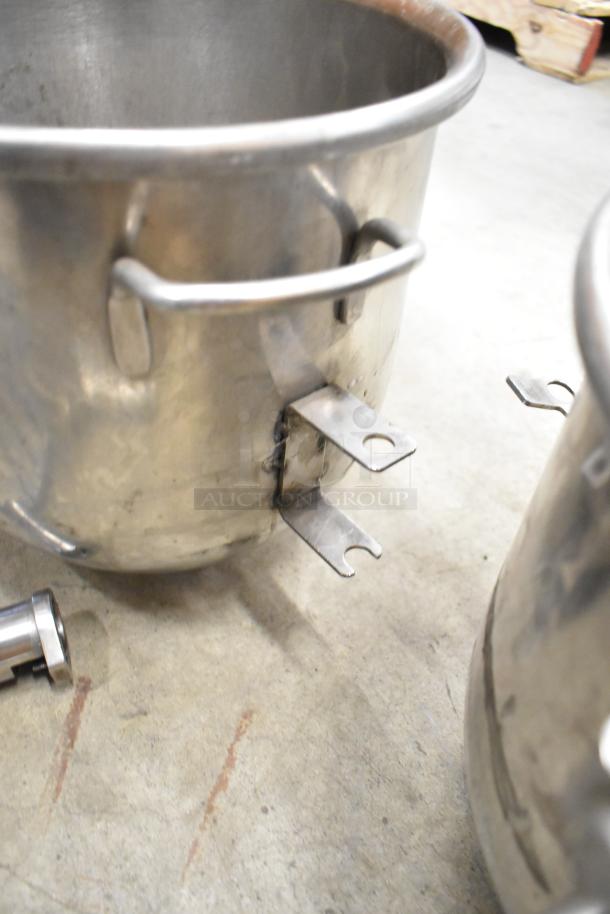 Stainless steel Hobart mixer items including two mixing bowls and paddle attachments, showing light wear.