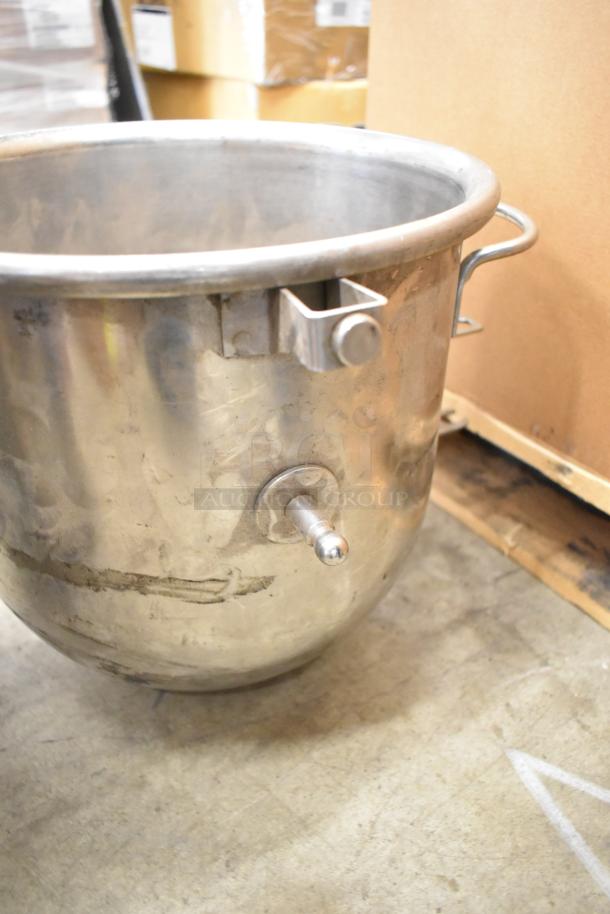 Hobart mixer stainless steel bowl, used condition, with attachment mounts visible, resting on a warehouse floor.