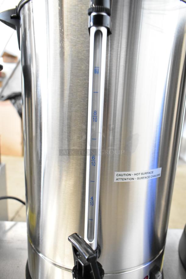 Avantco stainless steel coffee urn with a visible water level gauge and caution label indicating hot surface. Scratch and dent condition.