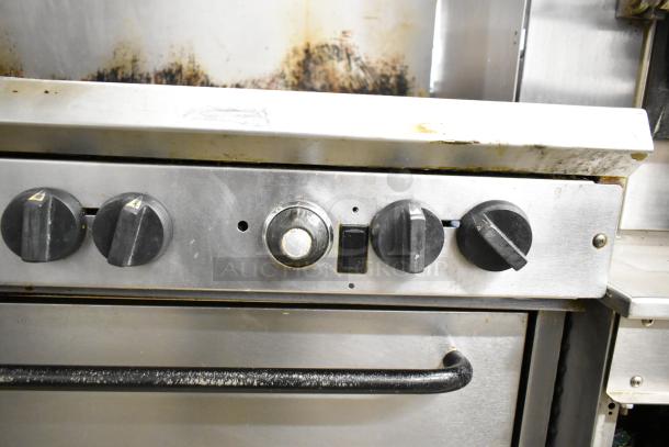 Southbend commercial gas range with 10 burners, dual ovens, overshelf, and backsplash. Visible control knobs, shows wear.