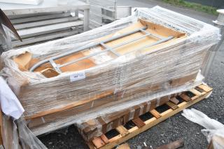 Pallet with shrink-wrapped items: cutting board, wire shelf. New, scratch and dent condition. Auction label visible.