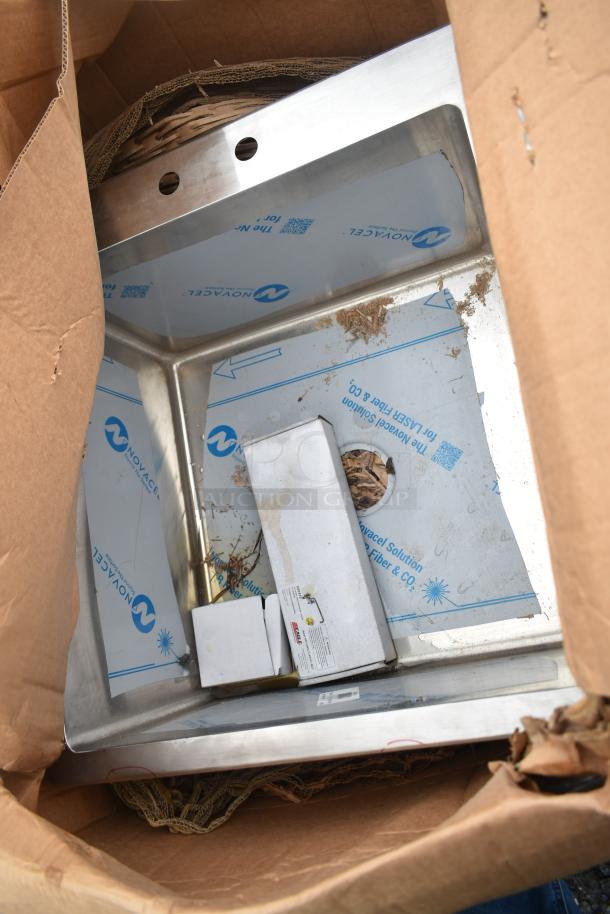 Brand new scratch and dent stainless steel sink partially covered with protective film in a cardboard package.