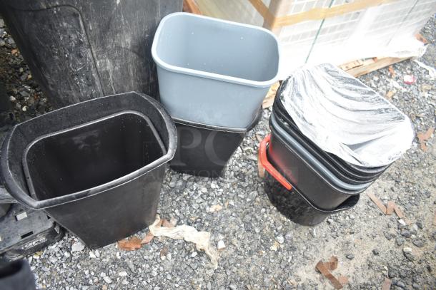 13 assorted poly trash cans, various sizes and colors, stacked outdoors, some wrapped in plastic, showing signs of wear.