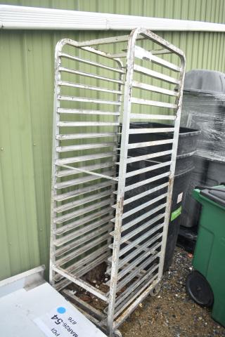 Metal commercial pan transport rack on casters, features multiple shelves. Slight rust visible, suitable for industrial use.