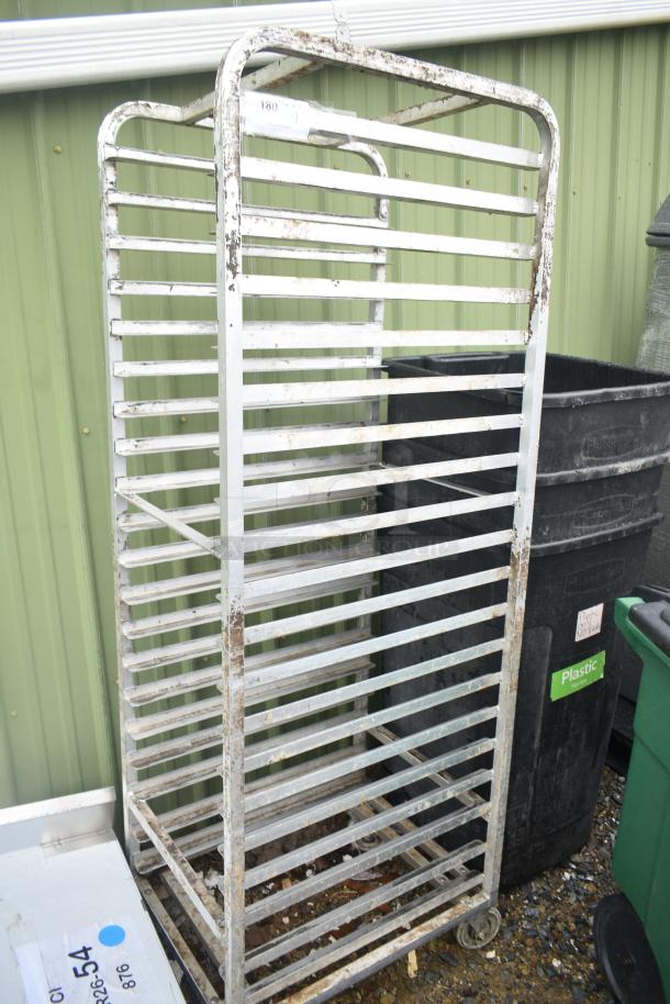 Metal commercial pan transport rack on casters, shows signs of wear and rust. Ideal for kitchen or bakery use.