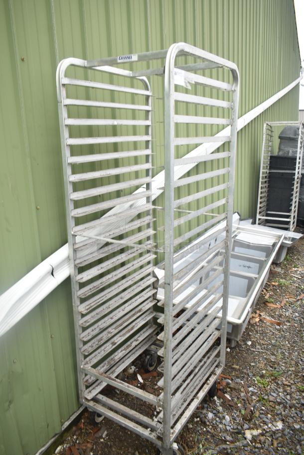 Commercial pan transport rack with multiple shelves on commercial casters, in used condition.