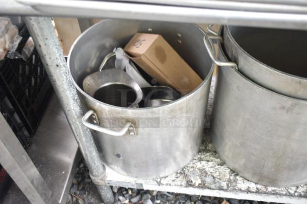 Commercial table with stock pots; stainless steel, used condition, includes four large pots, sturdy handles visible.