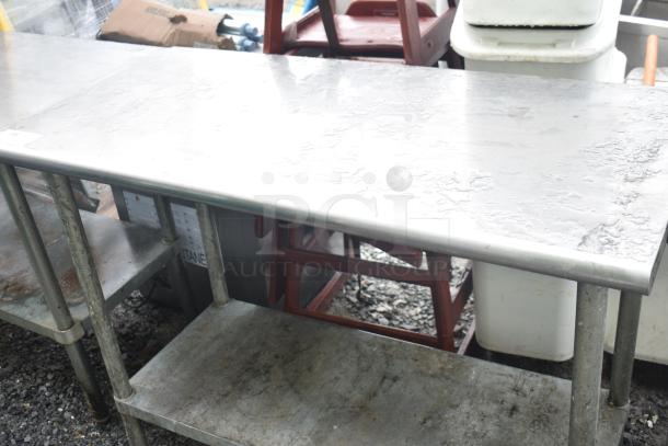 Commercial stainless steel table with under-shelf, showing signs of wear; ideal for kitchen use.
