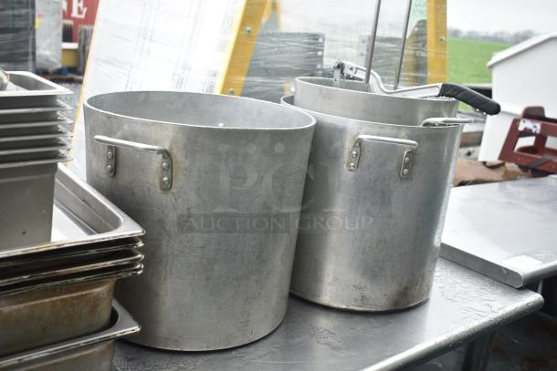 Metal commercial table with an under shelf, featuring large silver stock pots and stackable drop-in bins, in used condition.