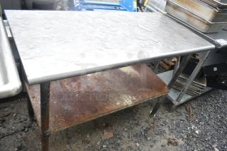 Commercial table with under shelf, metal top, visible rust on the lower shelf, in used condition.