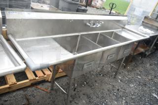 Commercial 3 bay sink with dual drain boards. Features labeled sections for wash, rinse, sanitize. Stainless steel, used condition.
