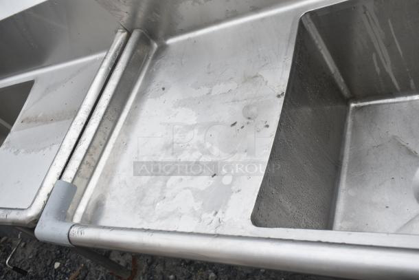 Commercial 3 bay stainless steel sink with dual drain boards, gently used, features visible wear and water stains.